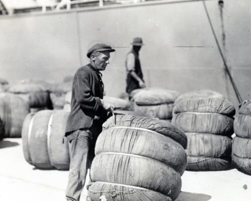 Man hauling bale of wool